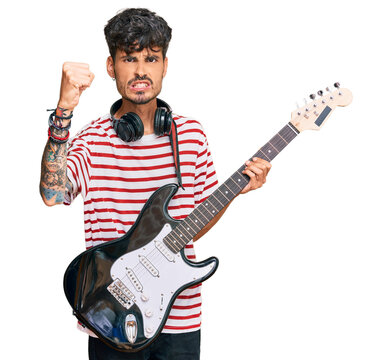 Young hispanic man playing electric guitar annoyed and frustrated shouting with anger, yelling crazy with anger and hand raised