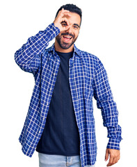 Young hispanic man wearing casual clothes doing ok gesture with hand smiling, eye looking through fingers with happy face.