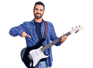 Young hispanic man playing electric guitar smiling happy pointing with hand and finger