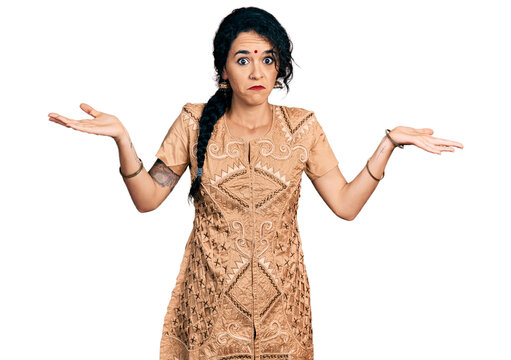 Young indian woman wearing traditional dress clueless and confused with open arms, no idea and doubtful face.