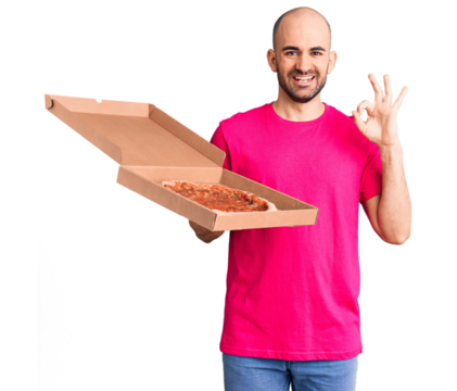 Young handsome man holding delivery pizza cardboard box doing ok sign with fingers, smiling friendly gesturing excellent symbol