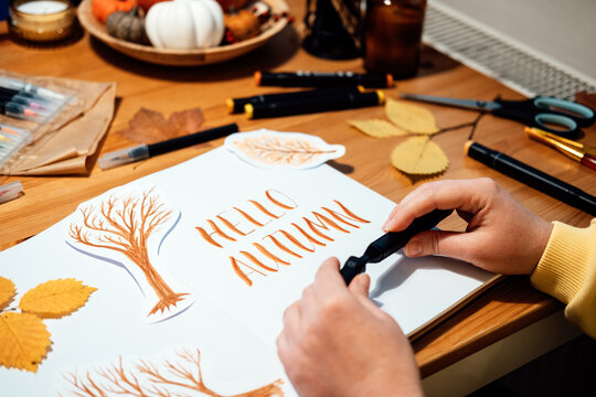 Hello Autumn lettering. Autumn Season Drawing, How to draw fall lettering drawing and painting. Fall lettering on the table with paints, brushes and autumn leaves