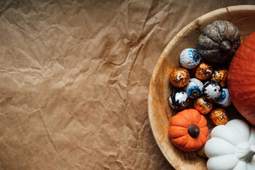 Sustainable Halloween. Eco-Friendly Halloween, plastic free trick-or-treating, Green Halloween. Zero waste Halloween decoration pumpkin, foil candy in wooden plate on table