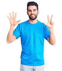 Naklejka premium Young handsome man with beard wearing casual t-shirt showing and pointing up with fingers number eight while smiling confident and happy.
