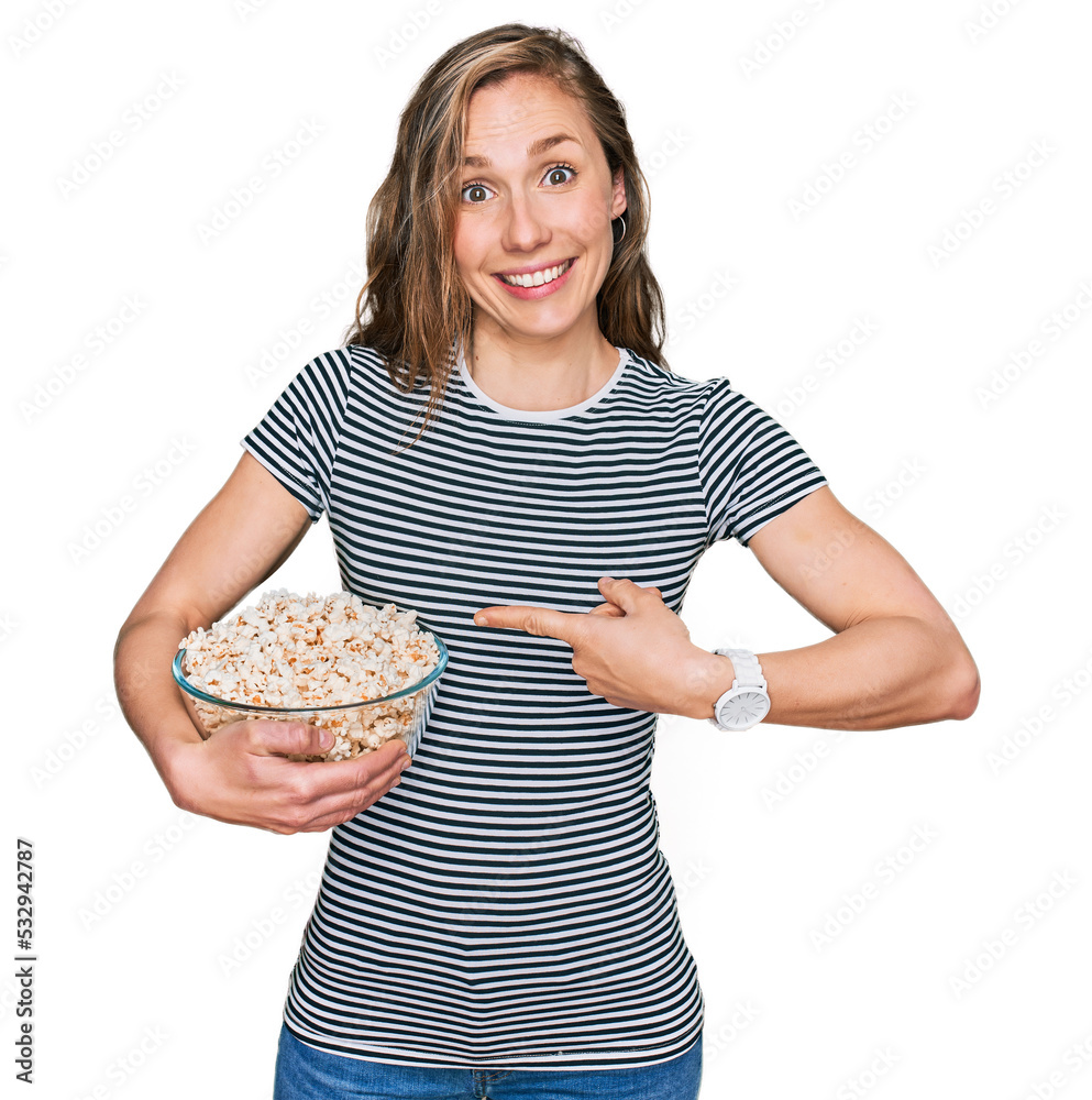 Poster young blonde woman eating popcorn smiling happy pointing with hand and finger