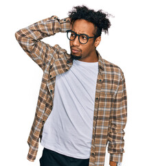 Young african american man with beard wearing casual clothes and glasses confuse and wondering...