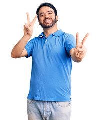 Young hispanic man wearing casual clothes smiling looking to the camera showing fingers doing victory sign. number two.