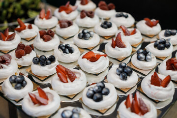 Meringue dessert Pavlova cake with fresh berries on a stone background. Pavlova berry cake with blueberries, strawberries, raspberries and on a dark background