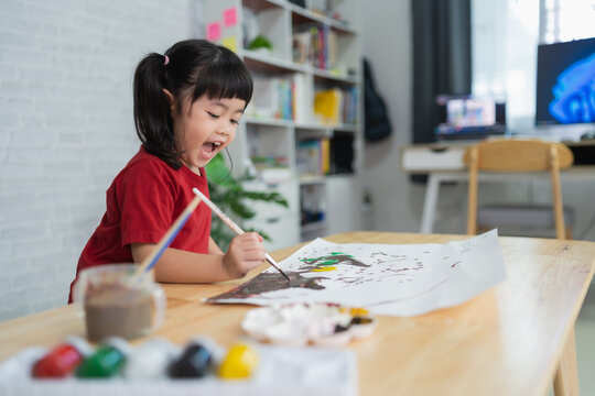 Cute little asian baby smiling and luagh painting with colorful paints using watercolor. Asian girl using paintbrush drawing color. Baby activity lifestyle concept.