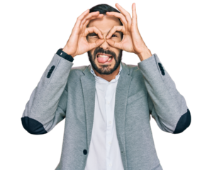 Young hispanic man wearing business clothes doing ok gesture like binoculars sticking tongue out, eyes looking through fingers. crazy expression.