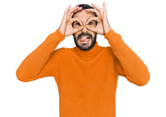 Young hispanic man wearing casual clothes doing ok gesture like binoculars sticking tongue out, eyes looking through fingers. crazy expression.