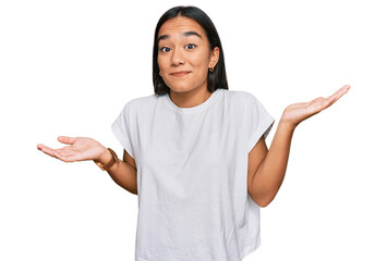 Young asian woman wearing casual white t shirt clueless and confused expression with arms and hands raised. doubt concept.