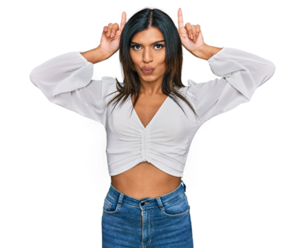 Young latin transsexual transgender woman wearing casual clothes doing funny gesture with finger over head as bull horns