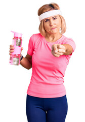 Young blonde woman wearing sportswear holding water bottle annoyed and frustrated shouting with anger, yelling crazy with anger and hand raised