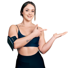 Young hispanic woman wearing sportswear amazed and smiling to the camera while presenting with hand and pointing with finger.