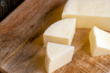 Fresh cow's milk cheese is cut on a board