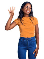 Young indian girl wearing casual clothes and glasses showing and pointing up with fingers number four while smiling confident and happy.