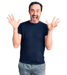 Naklejka premium Middle age handsome man wearing casual t-shirt celebrating crazy and amazed for success with arms raised and open eyes screaming excited. winner concept