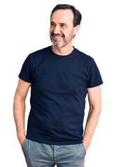 Middle age handsome man wearing casual t-shirt looking away to side with smile on face, natural expression. laughing confident.