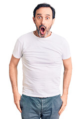 Middle age handsome man wearing casual t-shirt afraid and shocked with surprise and amazed expression, fear and excited face.