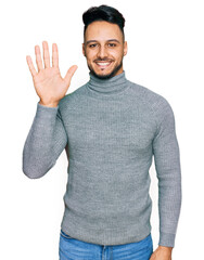 Naklejka premium Young arab man wearing casual clothes showing and pointing up with fingers number five while smiling confident and happy.