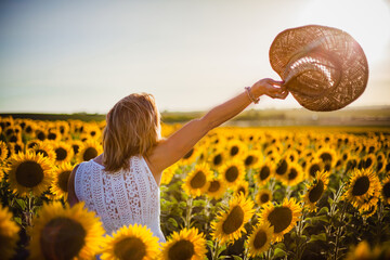 beautiful woman saying goodbye in the field of sunflowers near el puerto de santa maria in andalusia spain - obrazy, fototapety, plakaty