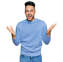Fototapeta premium Young arab man wearing casual clothes celebrating victory with happy smile and winner expression with raised hands