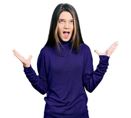 Young brunette girl with long hair wearing turtleneck sweater crazy and mad shouting and yelling with aggressive expression and arms raised. frustration concept.