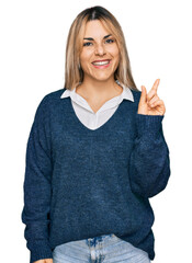 Young caucasian woman wearing casual clothes with a big smile on face, pointing with hand finger to the side looking at the camera.