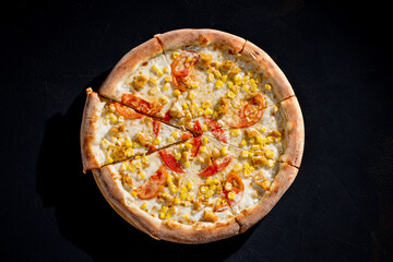 Pizza for children on a cream base with chicken fillet, tomatoes, corn and mozzarella cheese