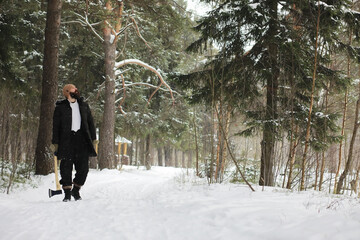 Outdoor portrait of handsome man in coat and scurf. Bearded man in the winter woods.