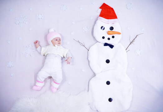 Newborn baby on a white background. Painting from white fabric. Snowman and baby. Christmas Holidays.