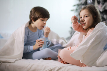 A family with children having fun on the bed under the covers during the Christmas holidays.