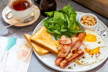 Breakfast with fried eggs, bacon, beans and fresh vegetables