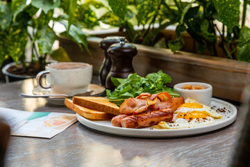 Breakfast with fried eggs, bacon, beans and fresh vegetables