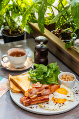 Breakfast with fried eggs, bacon, beans and fresh vegetables