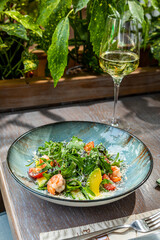 salad with shrimp, avocado, fresh vegetables and herbs, served with white wine