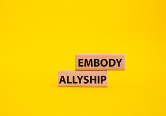 Embody Allyship symbol. Concept word Embody Allyship on wooden blocks. Beautiful yellow background....