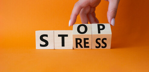 Stop and Stress symbol. Businessman hand turnes wooden cubes and changes word Stress to Stop. Beautiful orange background. Business and Stop Stress concept. Copy space.