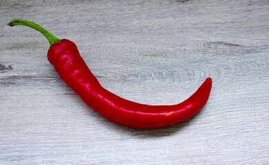 Hot red pepper on a gray background. Green tail, spicy seasoning.