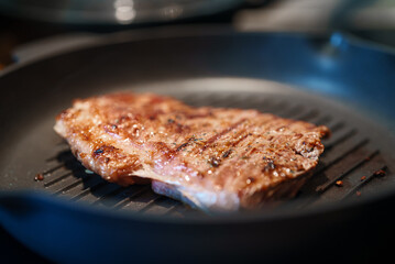 Beef entrecote is fried in a pan.