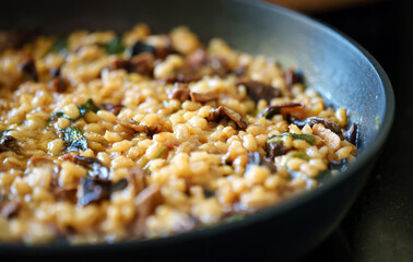 Golden orzotto with pearl barley preparing in pan.