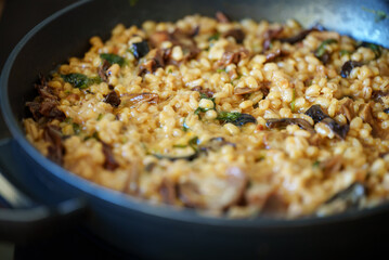 Golden orzotto with pearl barley preparing in pan.