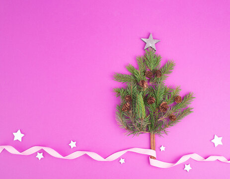 Christmas tree made from fir branches, pine cones  and a cinnamon stick as the trunk, pink greeting card with copy space