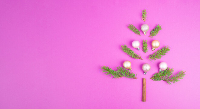 Christmas tree made from fir branches, pink baubles and a cinnamon stick as the trunk, greeting card with copy space