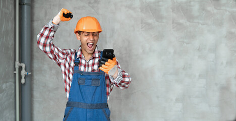 Photo of a happy positive young man builder in helmet posing isolated over gray wall background...