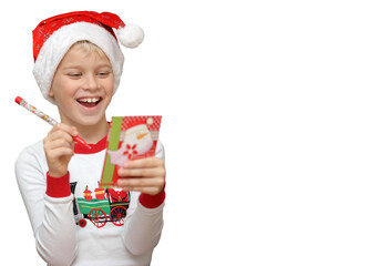 Cute little child wearing Santa hat and writing a wishlist on white background. Isolated object, christmas holiday