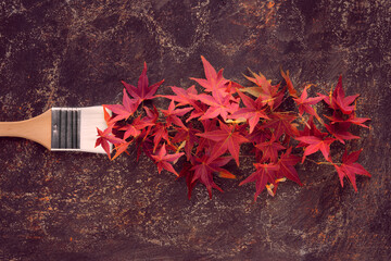 Brush loaded with paint made from red maple leaves. Concept image, seasonal Autumn home renovation background in warm brown, red and orange colors.