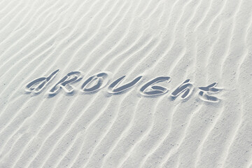 Fototapeta na wymiar drought written with finger on white sand, word climate change concept on sand