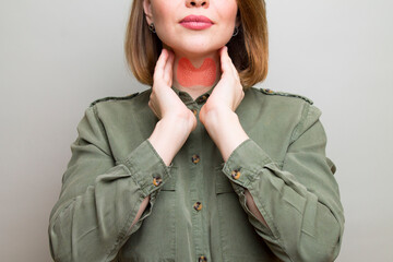 Female checking thyroid gland by herself. Thyroid disorder includes goiter, hyperthyroid,...